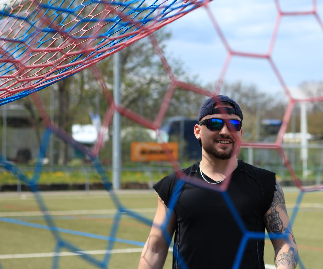 Nate Bock in sunglasses, seen through a goal net.